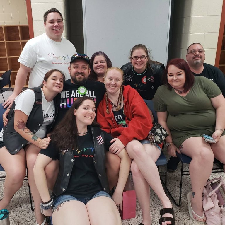 A diverse group of smiling people posing together in a casual setting.